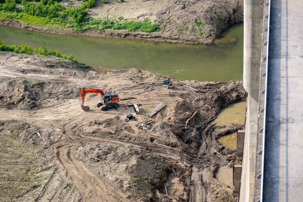 Heavy machinery clearing land near a dam on a rural property